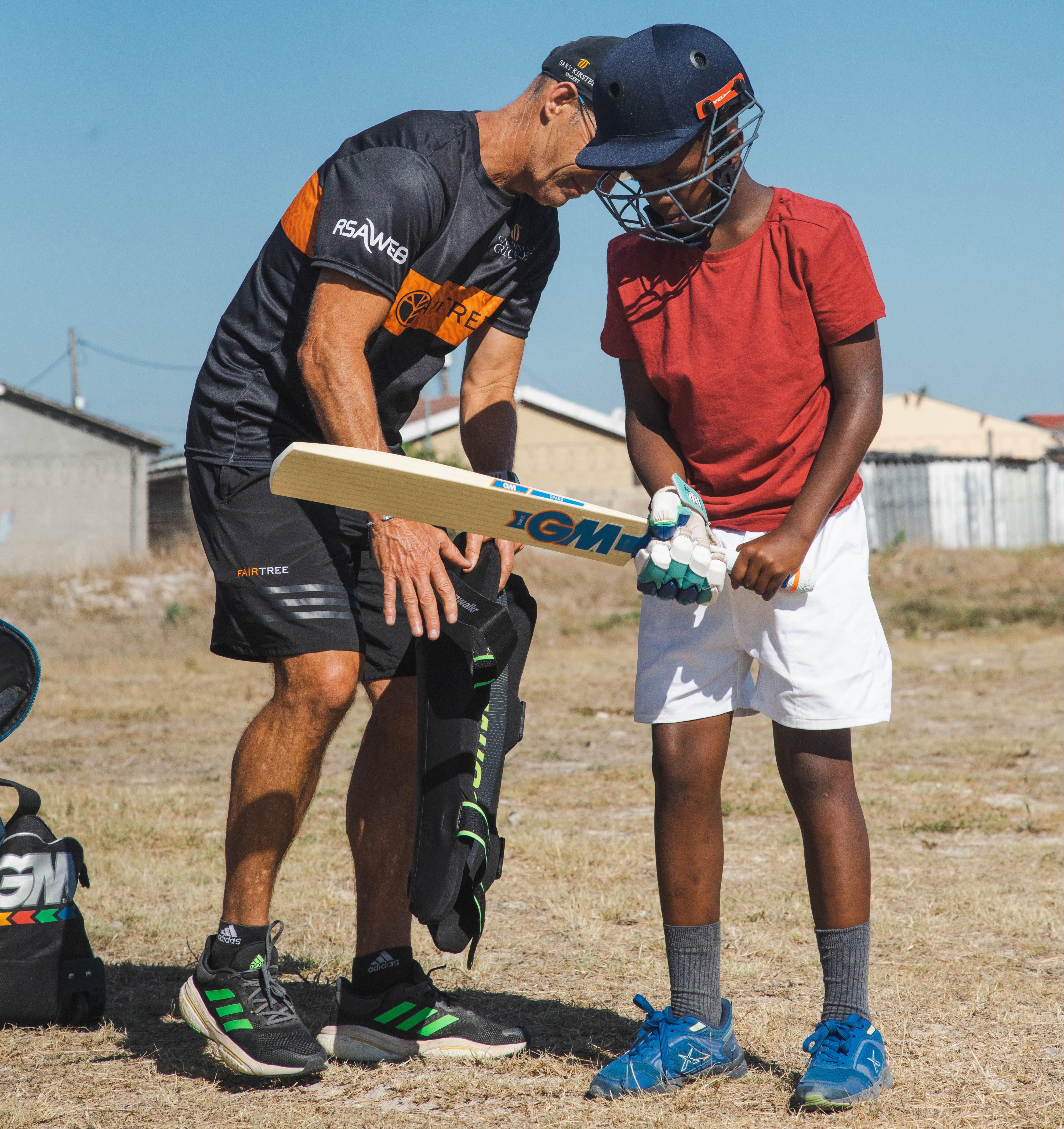 A child holding a cricket bat and wearing a helmet