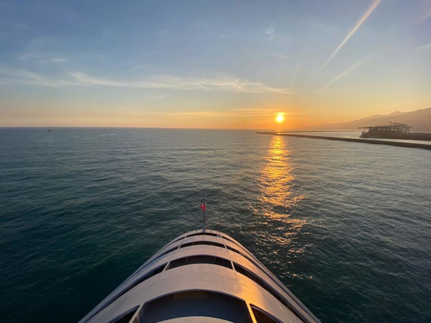 A Virgin Voyage cruise ship sailing towards the sunset