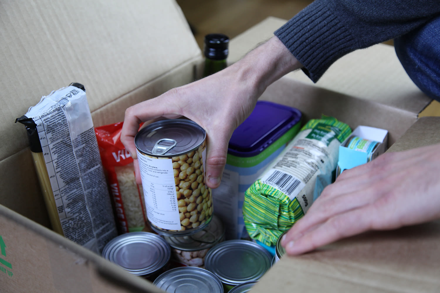 A person reaching into a donated box of food at a food bank