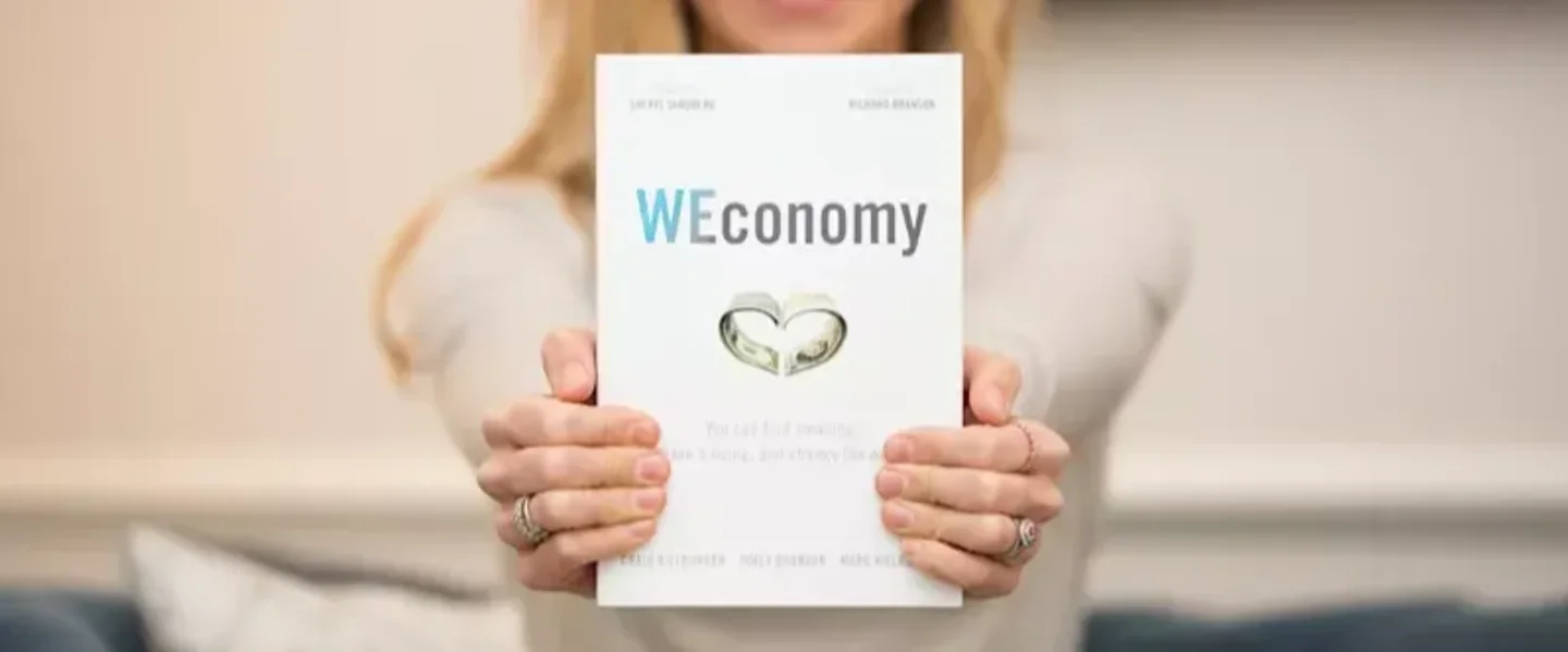 Holly Branson holding copy of WEConomy to the camera