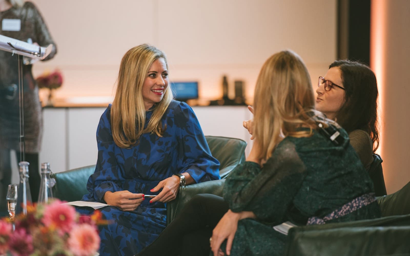 Holly Branson sits speaking to female founders, She wears a dark blue dress with her blonde hair over her shoulders