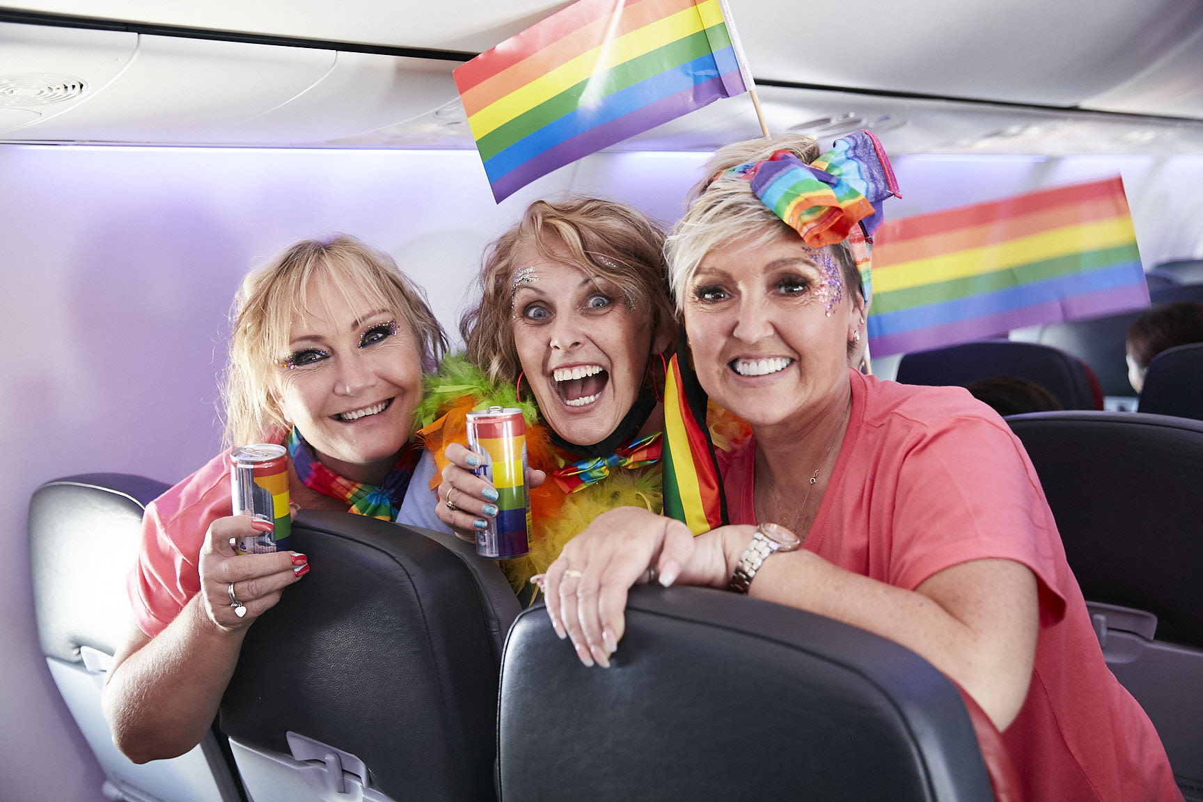 Three women holding rainbow flags on board Virgin Australia's 2021 Pride Flight