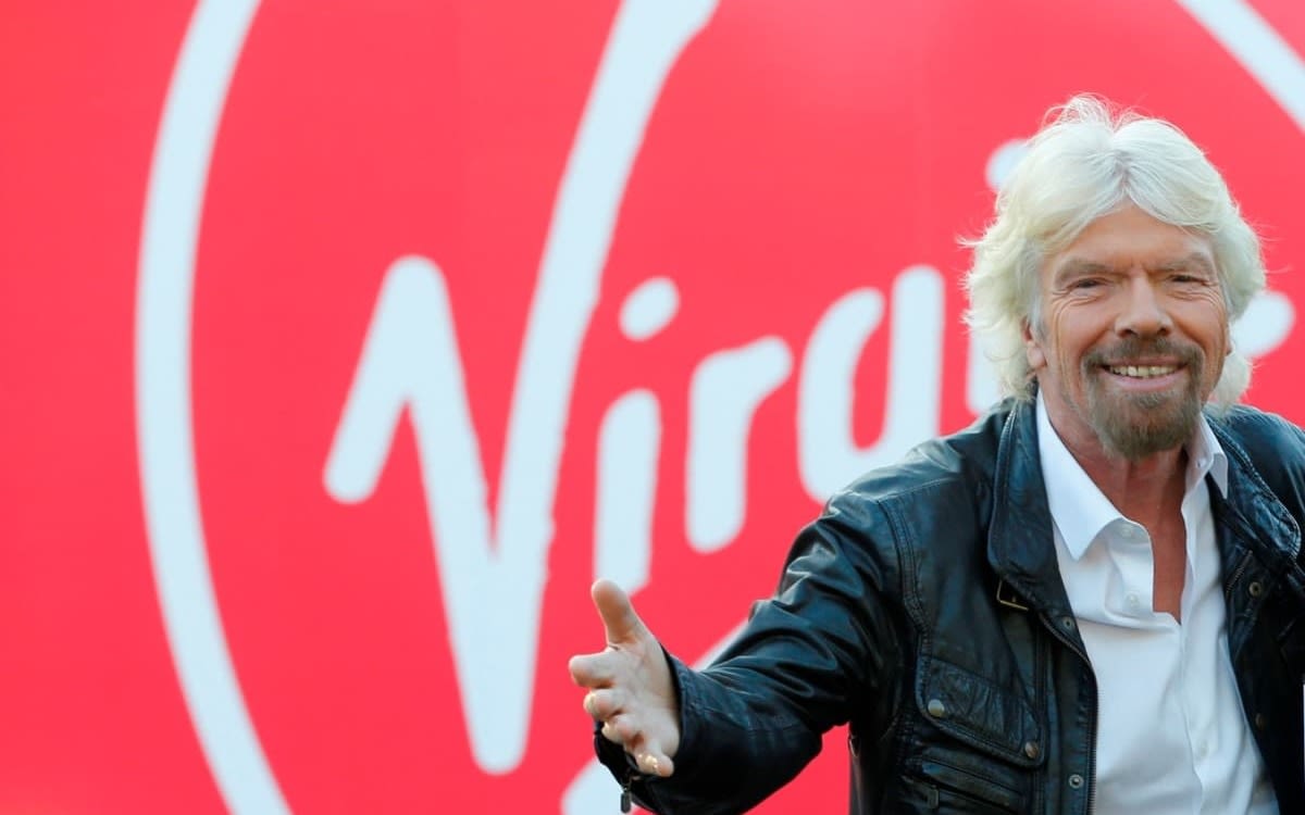 Richard Branson standing in front of the Virgin logo