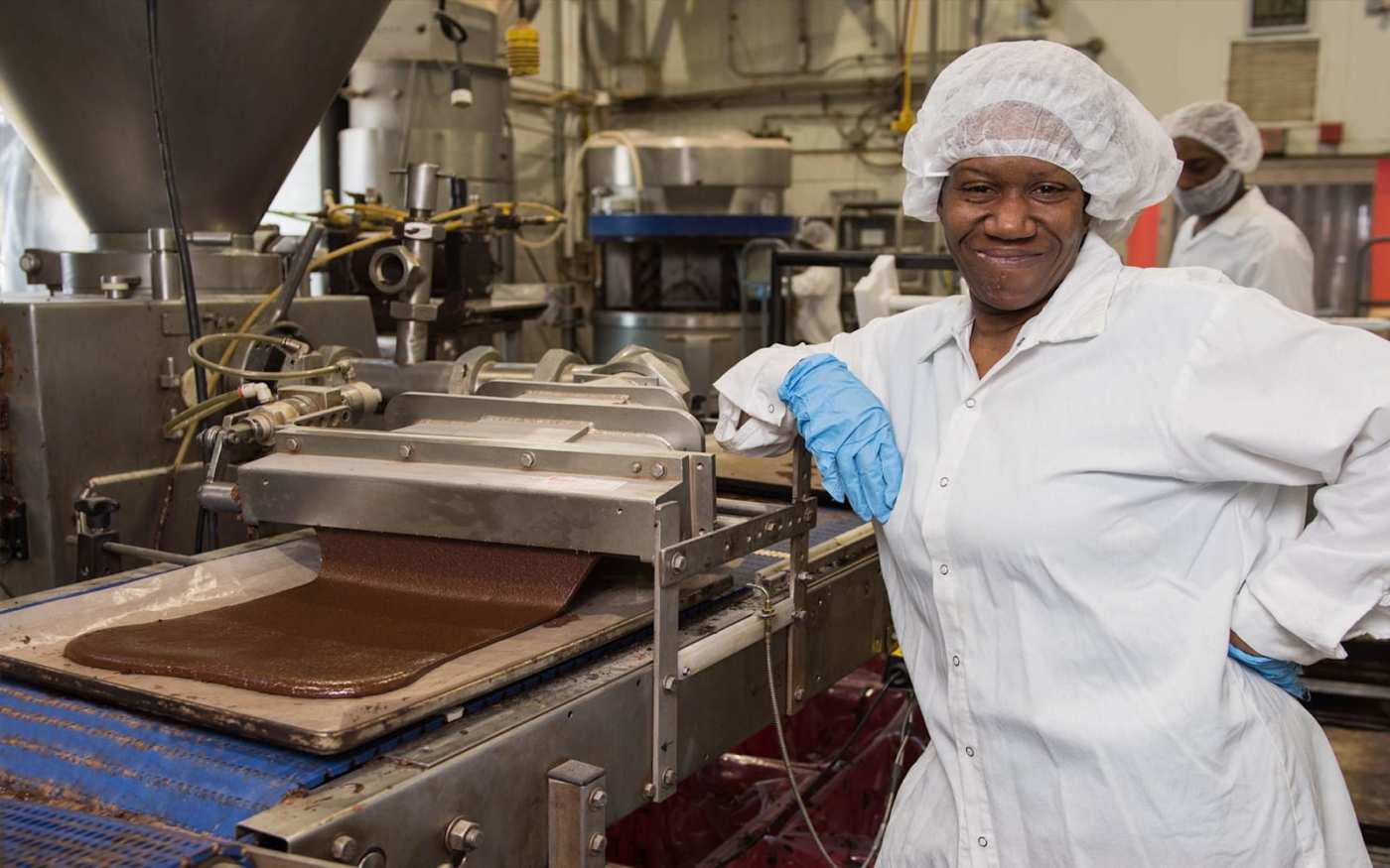 A baker smiling at the camera in her bakery