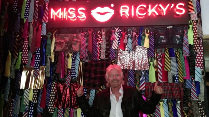 Richard Branson stands in front of a wall of cut off ties at Miss Ricky's at Virgin Hotels Chicago