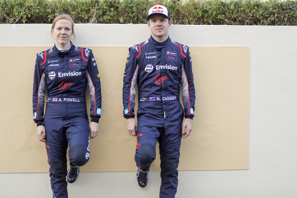 Two Envision Virgin Racing drivers, one female, one male, standing against a wall