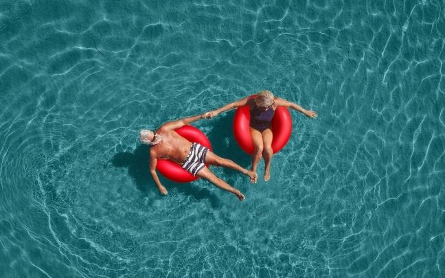An image of a couple in the ocean in red floaties. 