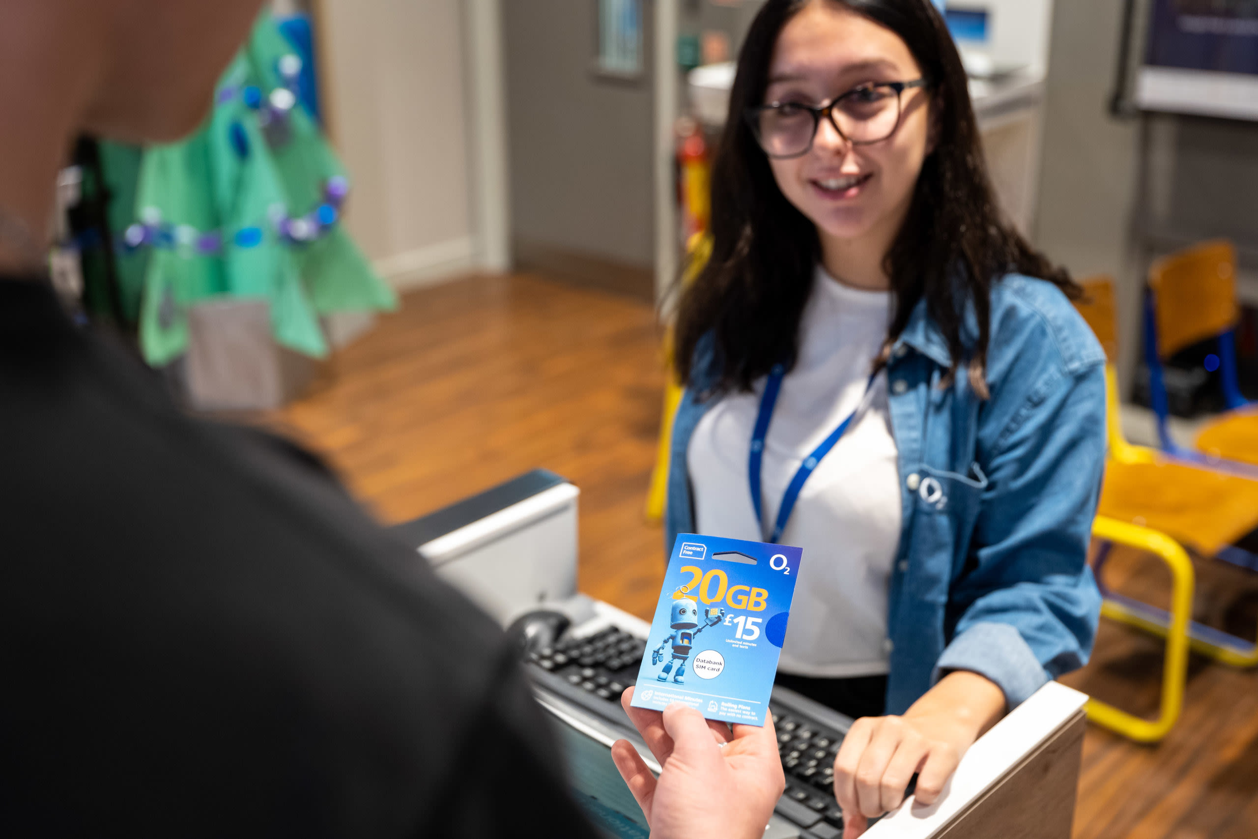 An O2 store employee handing a National Databank SIM card to a customer