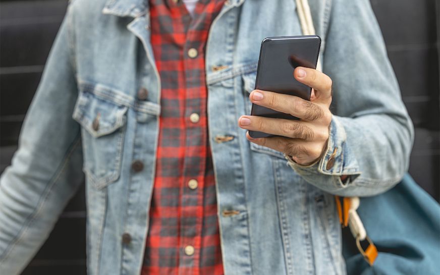 A man's hand holding a smartphone | Shutterstock