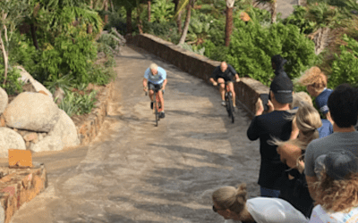 Bike riders riding up a hill with people cheering them on 