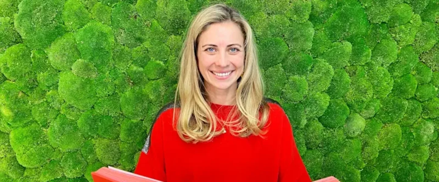 Holly Branson smiling at the camera, standing in front of a green, textured wall