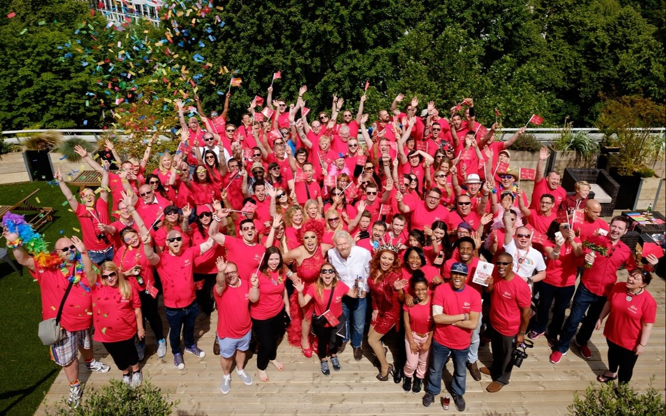 Richard Branson stands with Virgin employees in red tshirts celebrating Pride