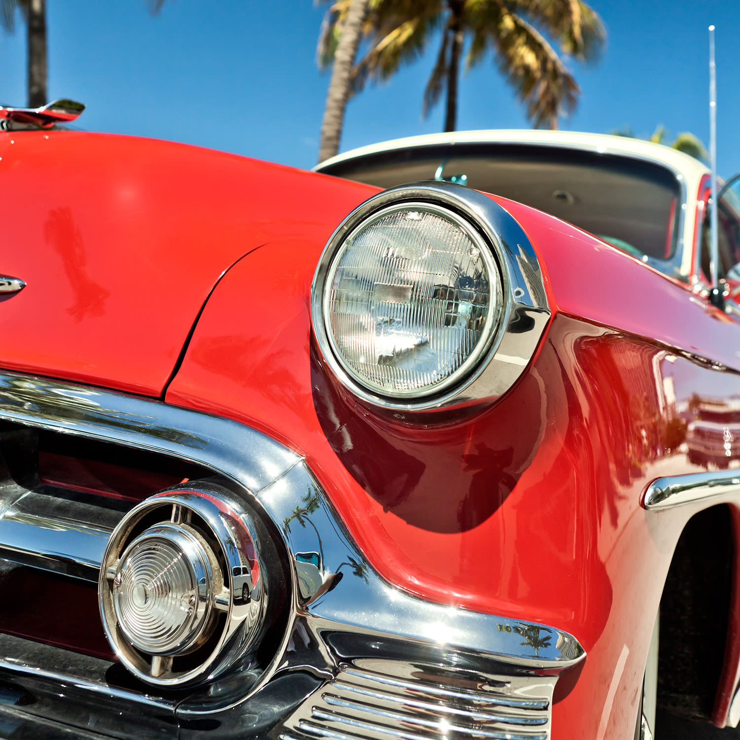 A red 1950s car in a tropical location