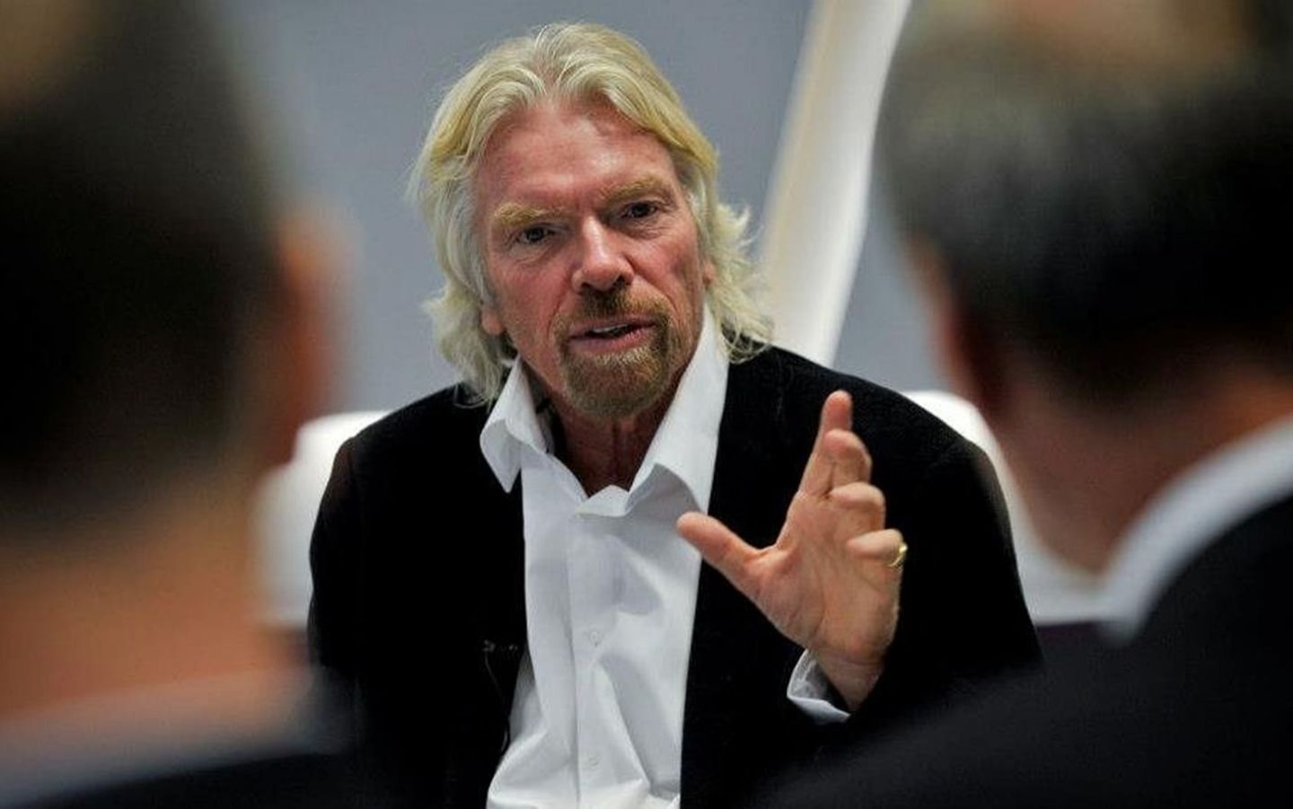 Richard Branson speaking to two men who have their backs to the camera
