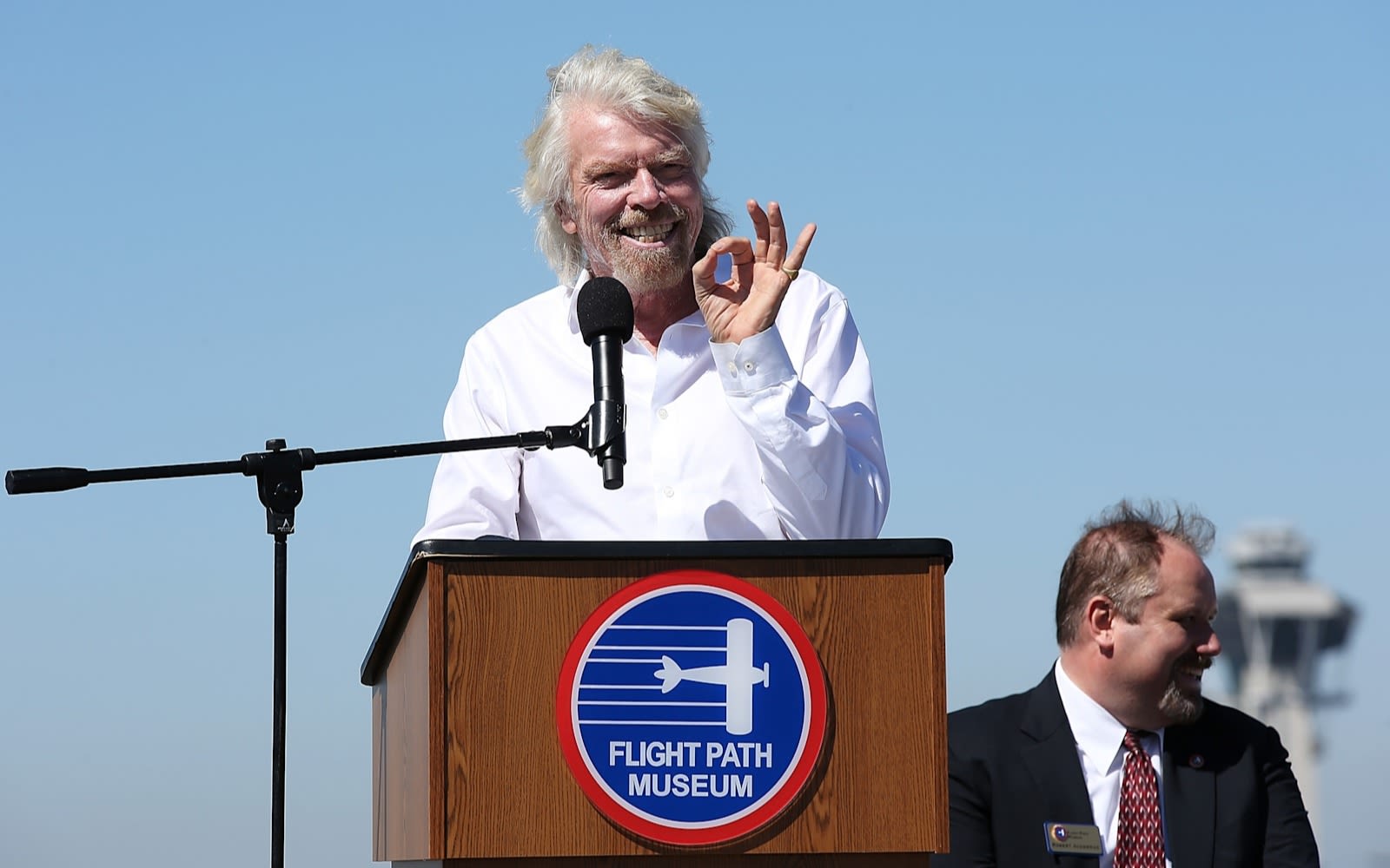 Richard Branson smiles while giving a speech at the Flight Path Museum