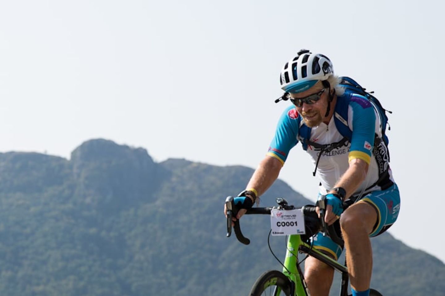 Richard Branson road cycling with mountain in the background