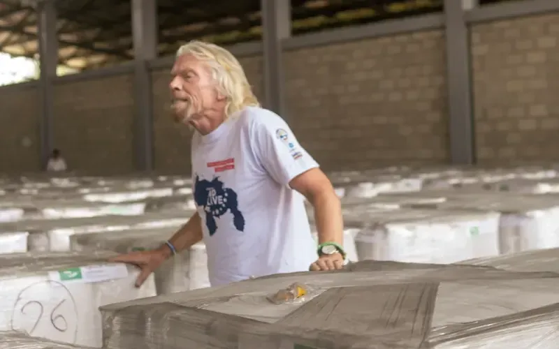 Richard Branson standing in-between loaded pallets 