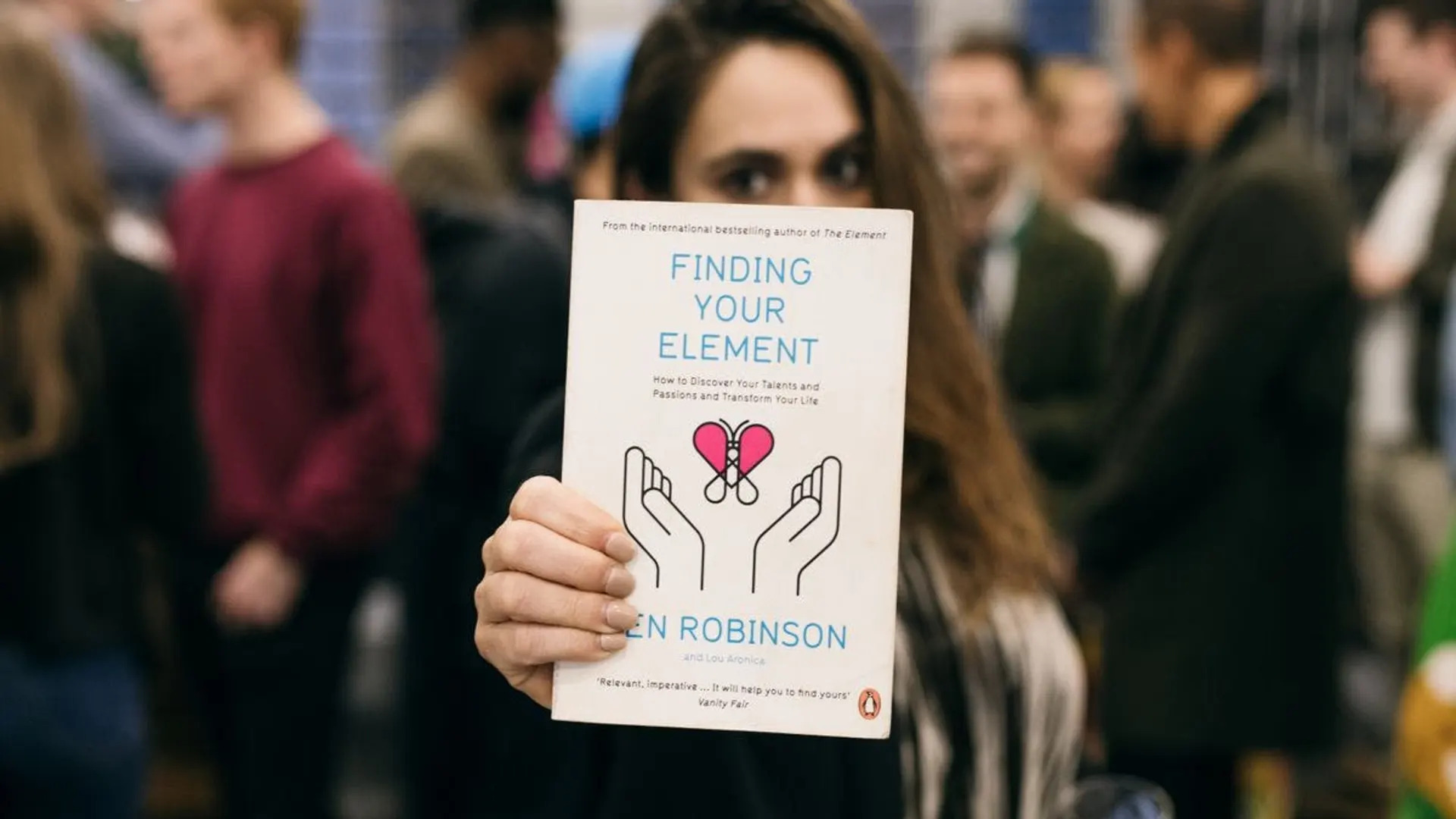 A woman holding a copy of the book Finding Your Element to the camera