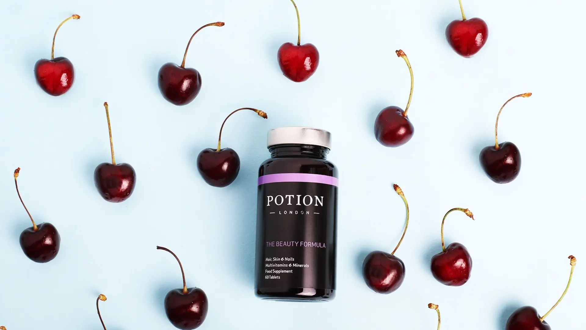 A bottle of Potion London Beauty London surrounded by cherries