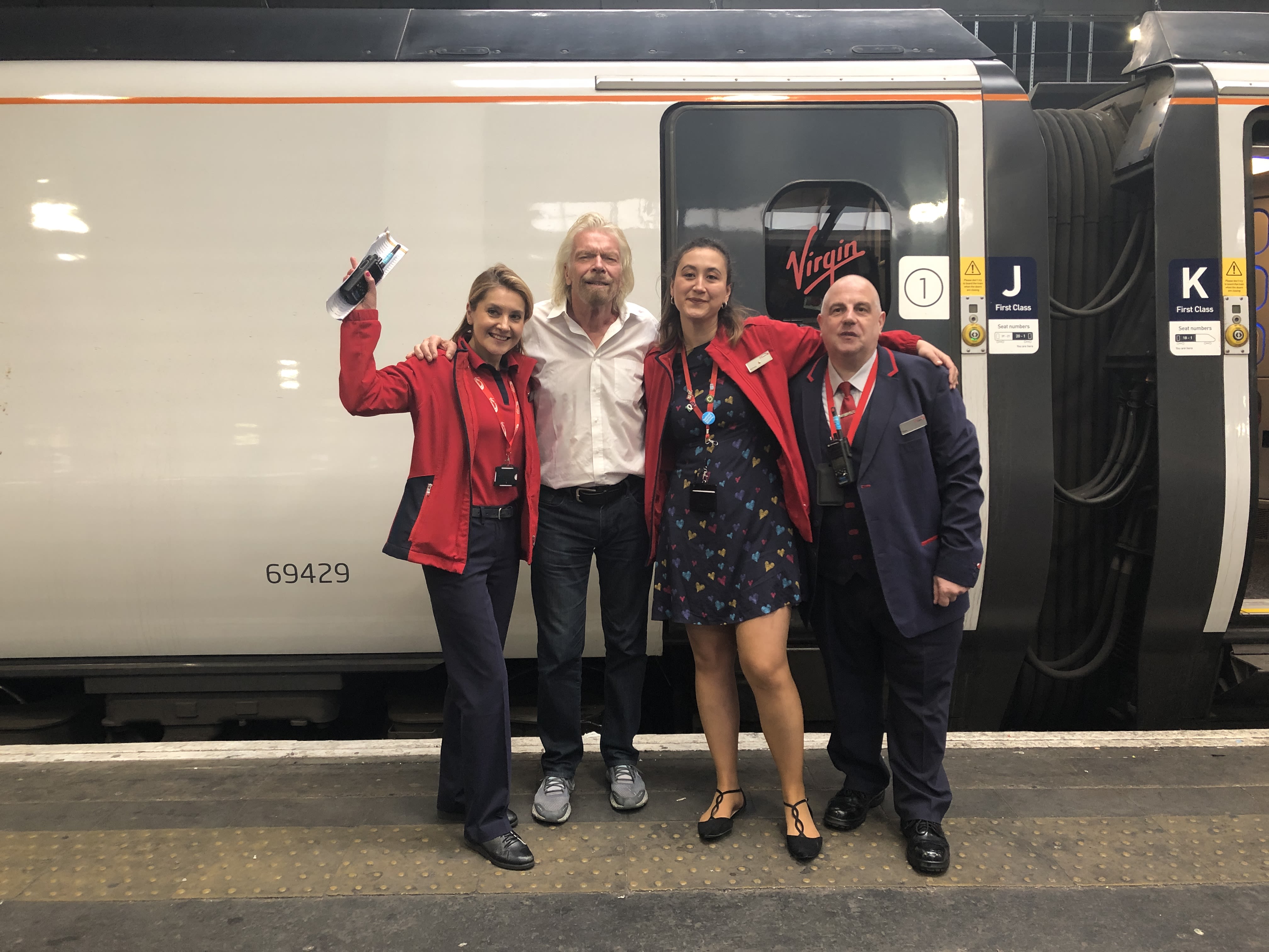 Richard Branson with Virgin Trains staff in front of a Virgin Train