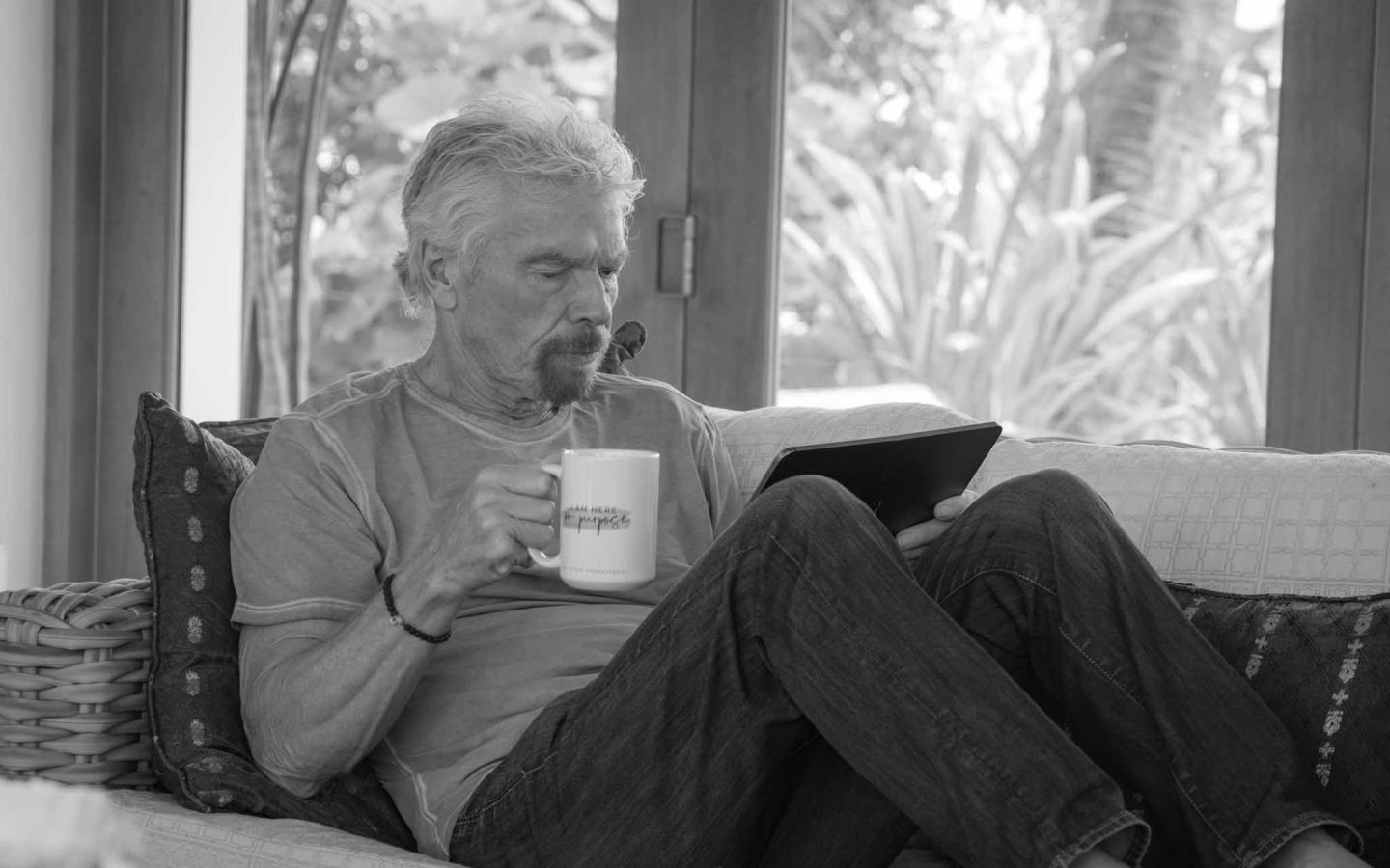 Richard Branson reading his ipad while having a cup of tea