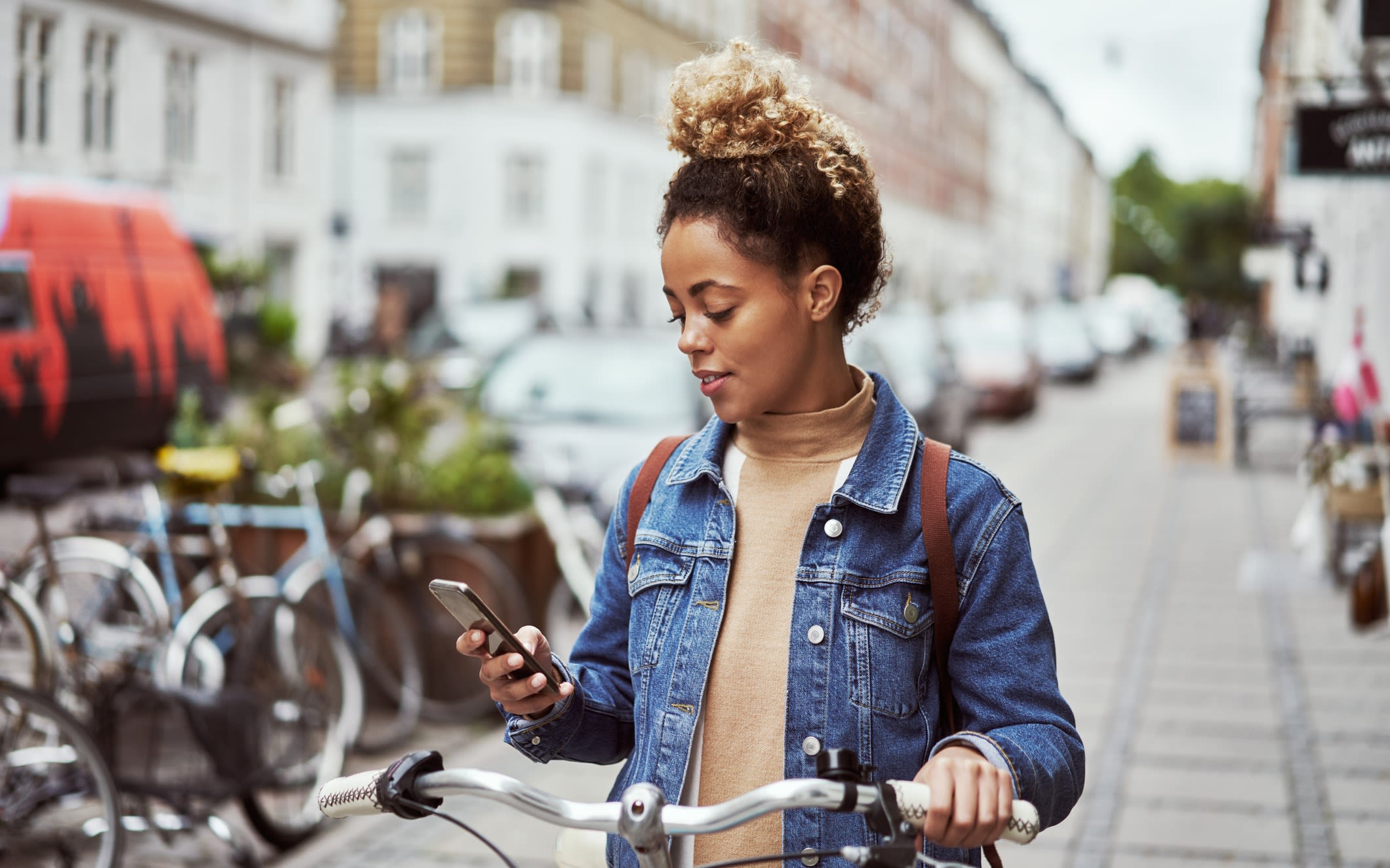 A woman standing with a bike, using a phone
