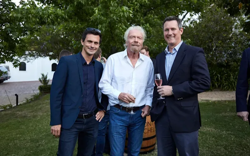 Richard Branson alongside two other men holding champagne flutes