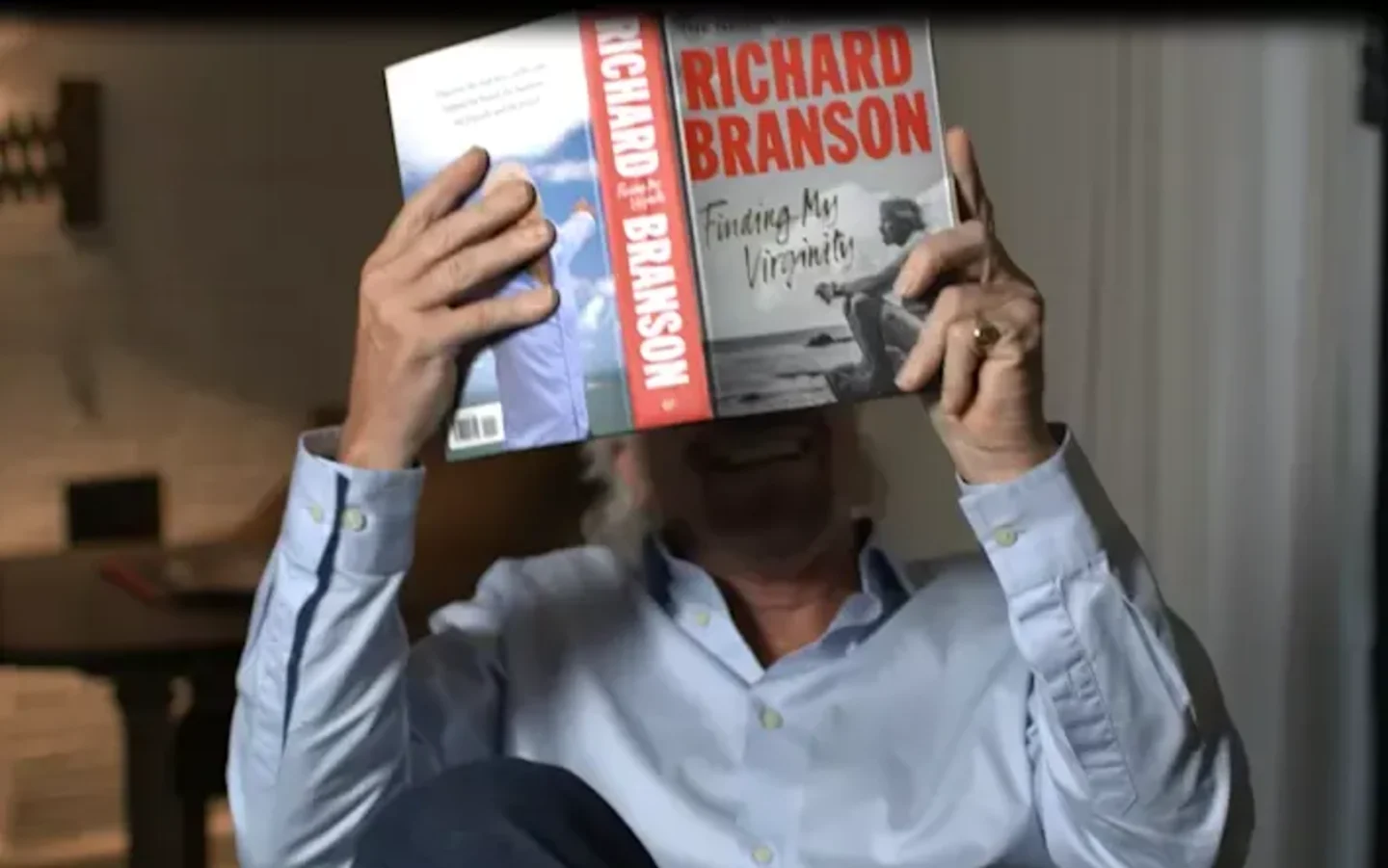 Richard Branson holds up his open auto-biography "Finding My Virginity"