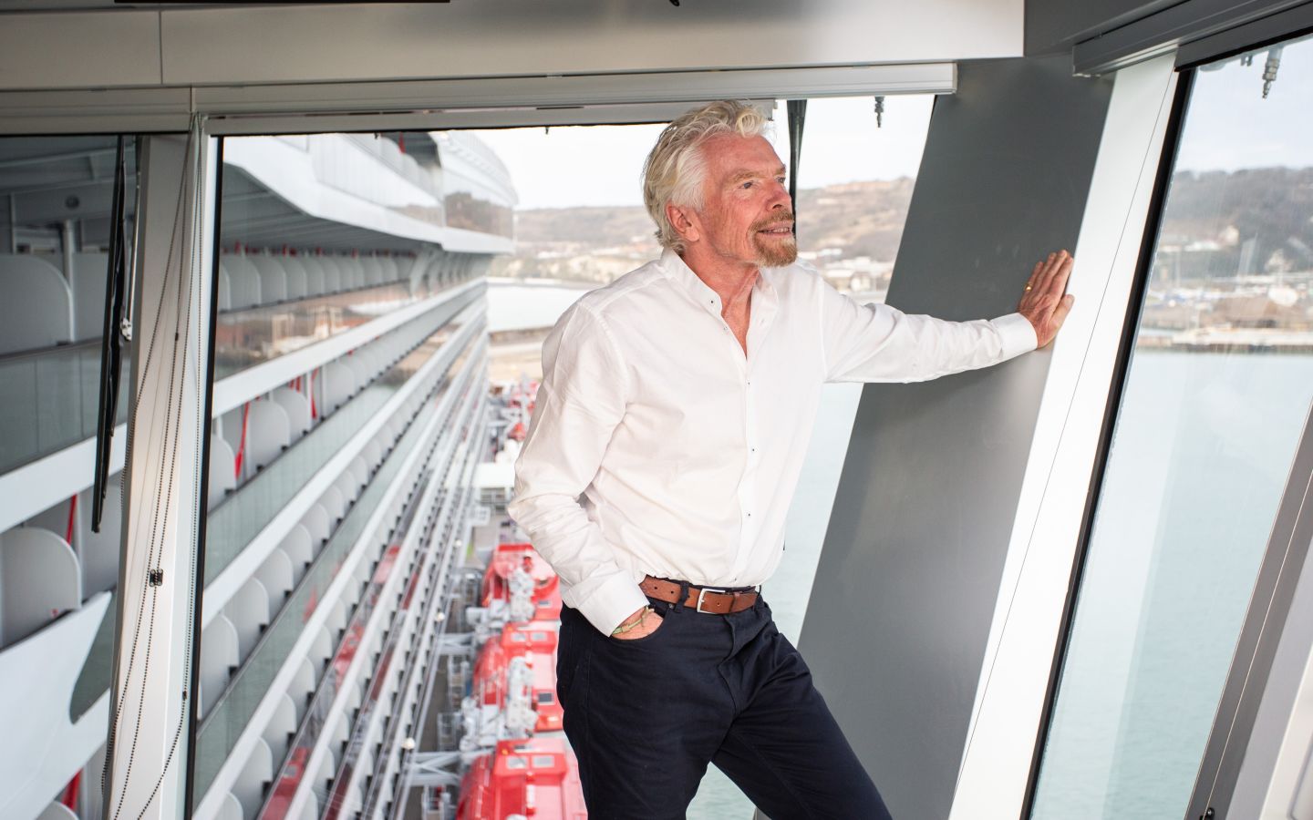 Richard Branson on board Virgin Voyages' ship, looking out of the window across the sea