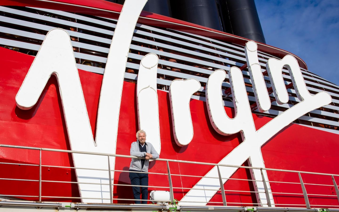 Richard Branson smiling on the back deck of Scarlet Lady - Virgin Voyages first ship