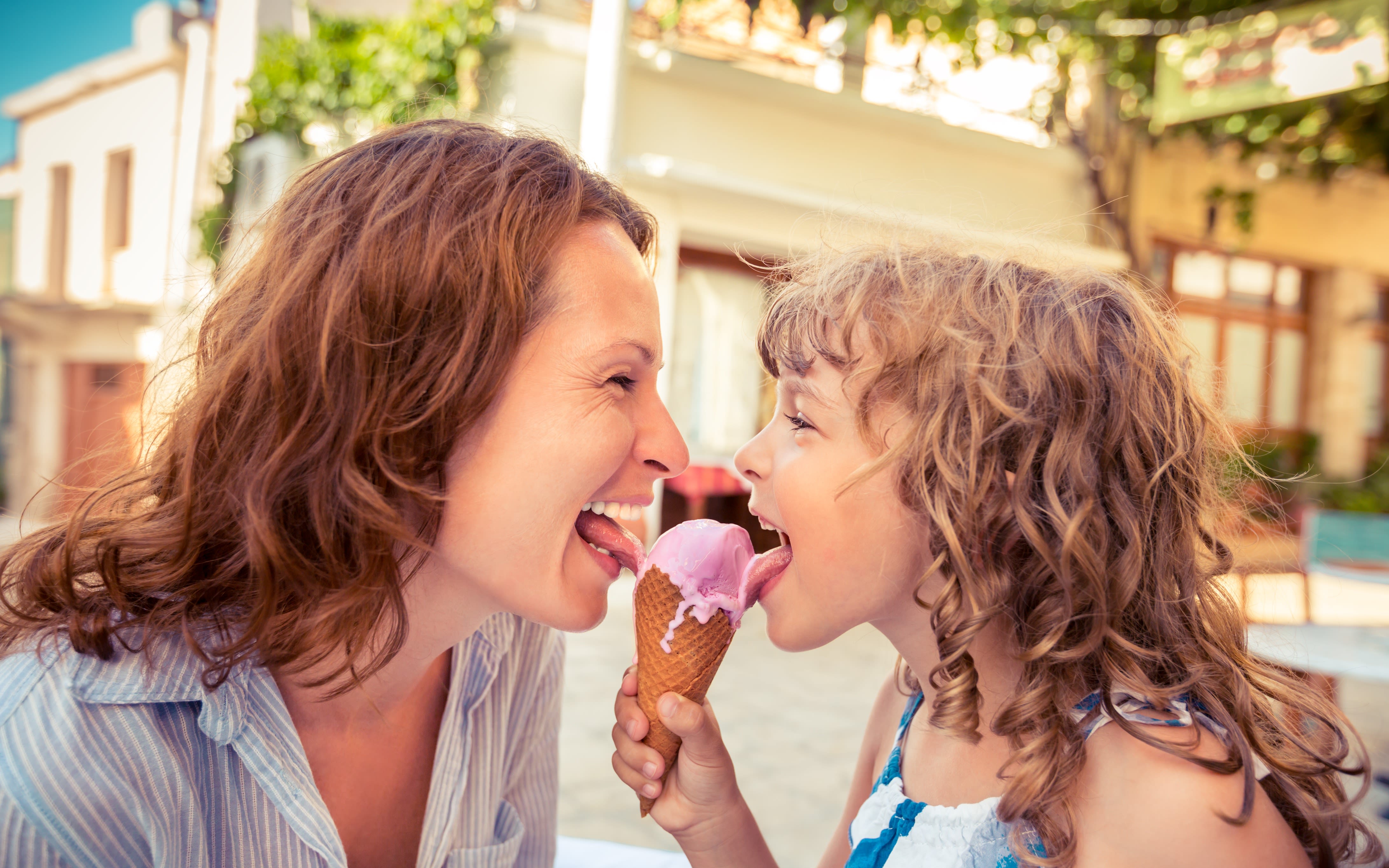 Mother and child eating ice cream in summer cafe outdoors.