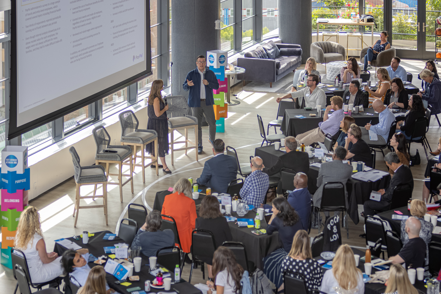 Alison Omens, President at JUST Capital and Tyler Spalding, Senior Director of Corporate Affairs & Global Head of Social Innovation at PayPal present to a room full of people at a 100% Human at Work gathering in New York