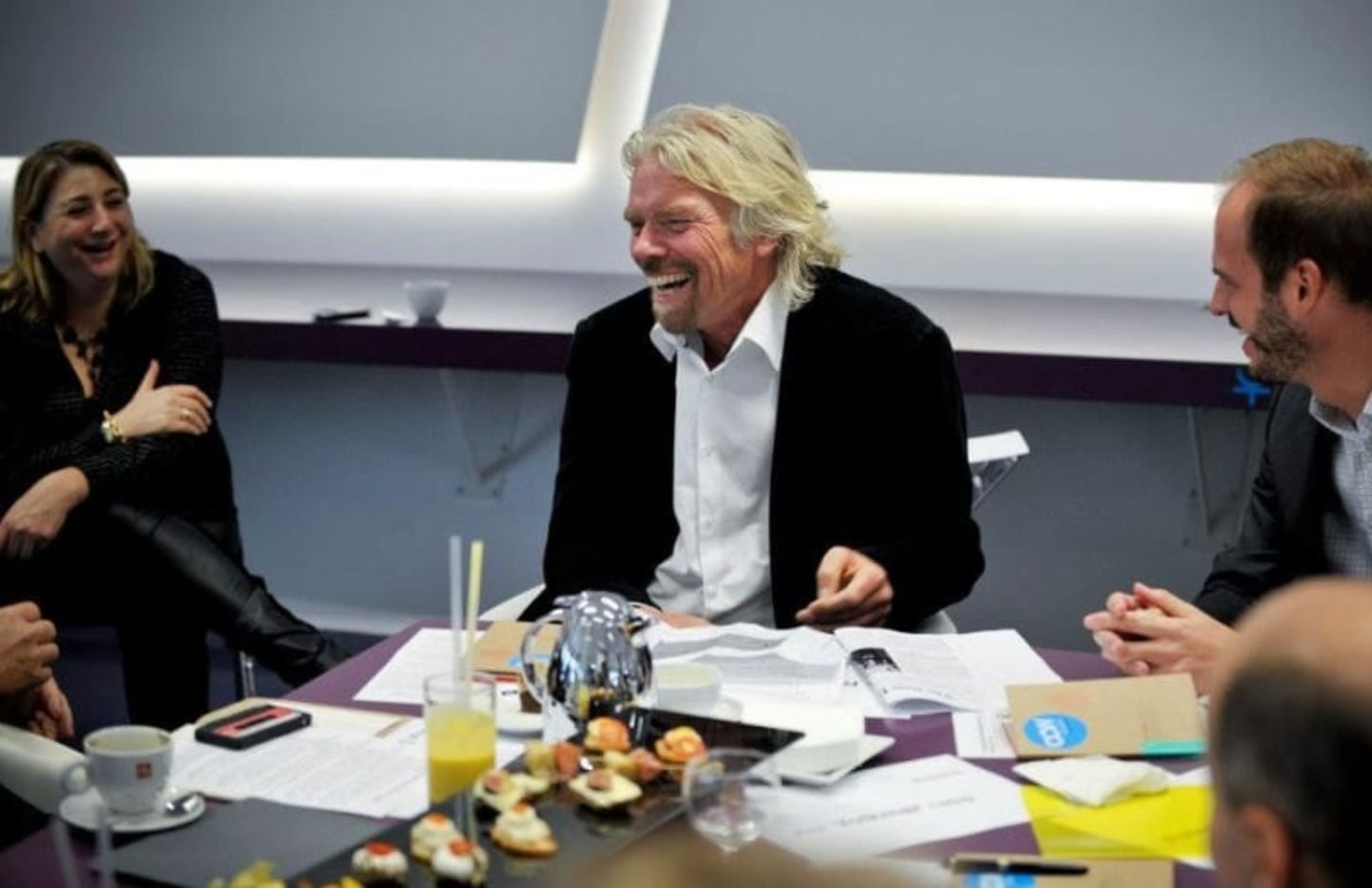 Richard Branson, sat in a meeting, laughing 