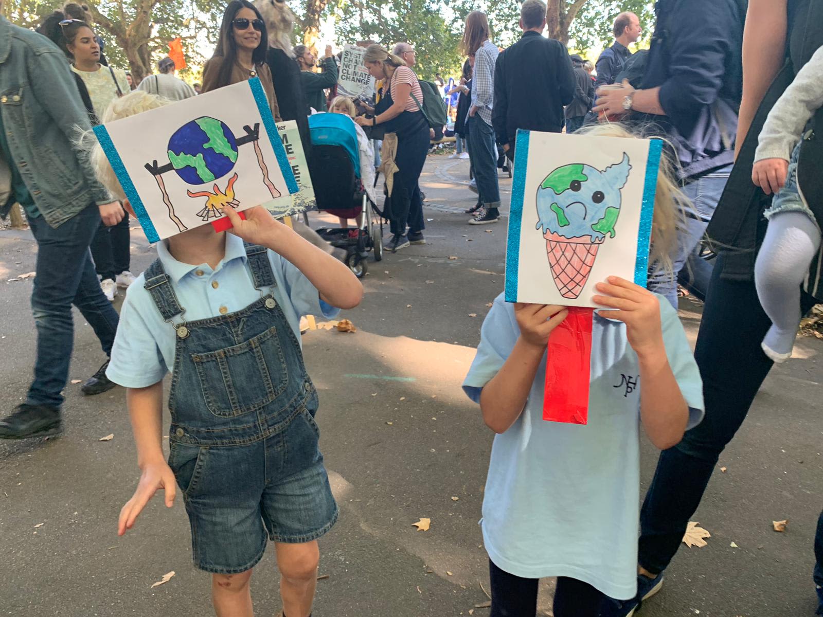 Etta and Artie Andrewes on a climate strike march, holding posters they've made to cover their faces