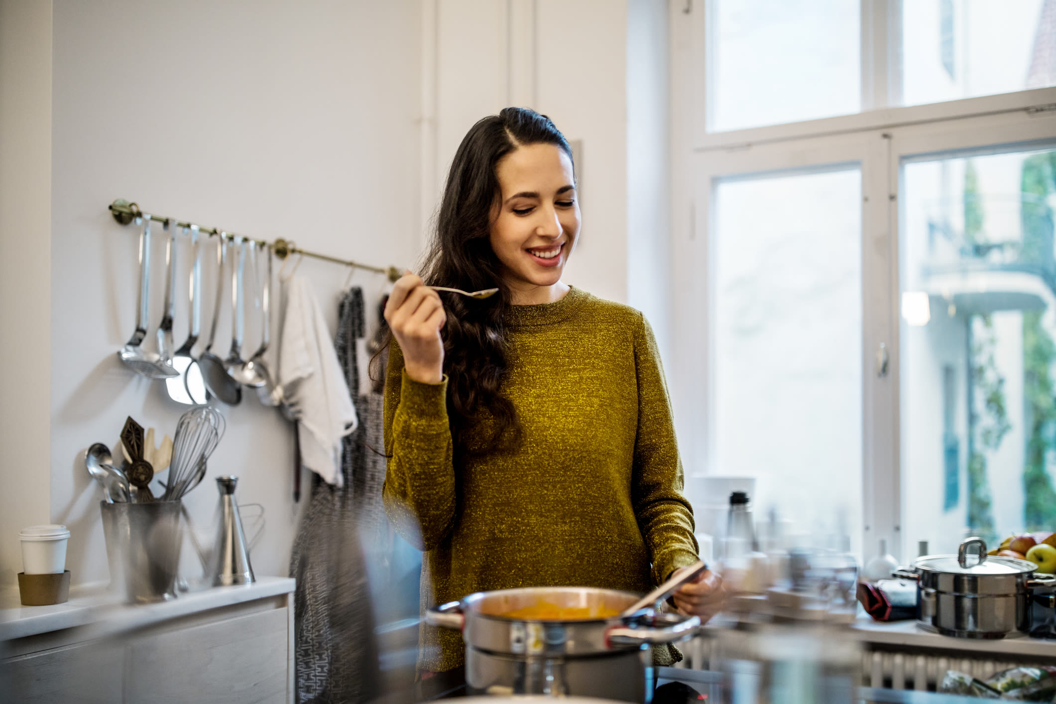 A woman tasting soup after she has made it