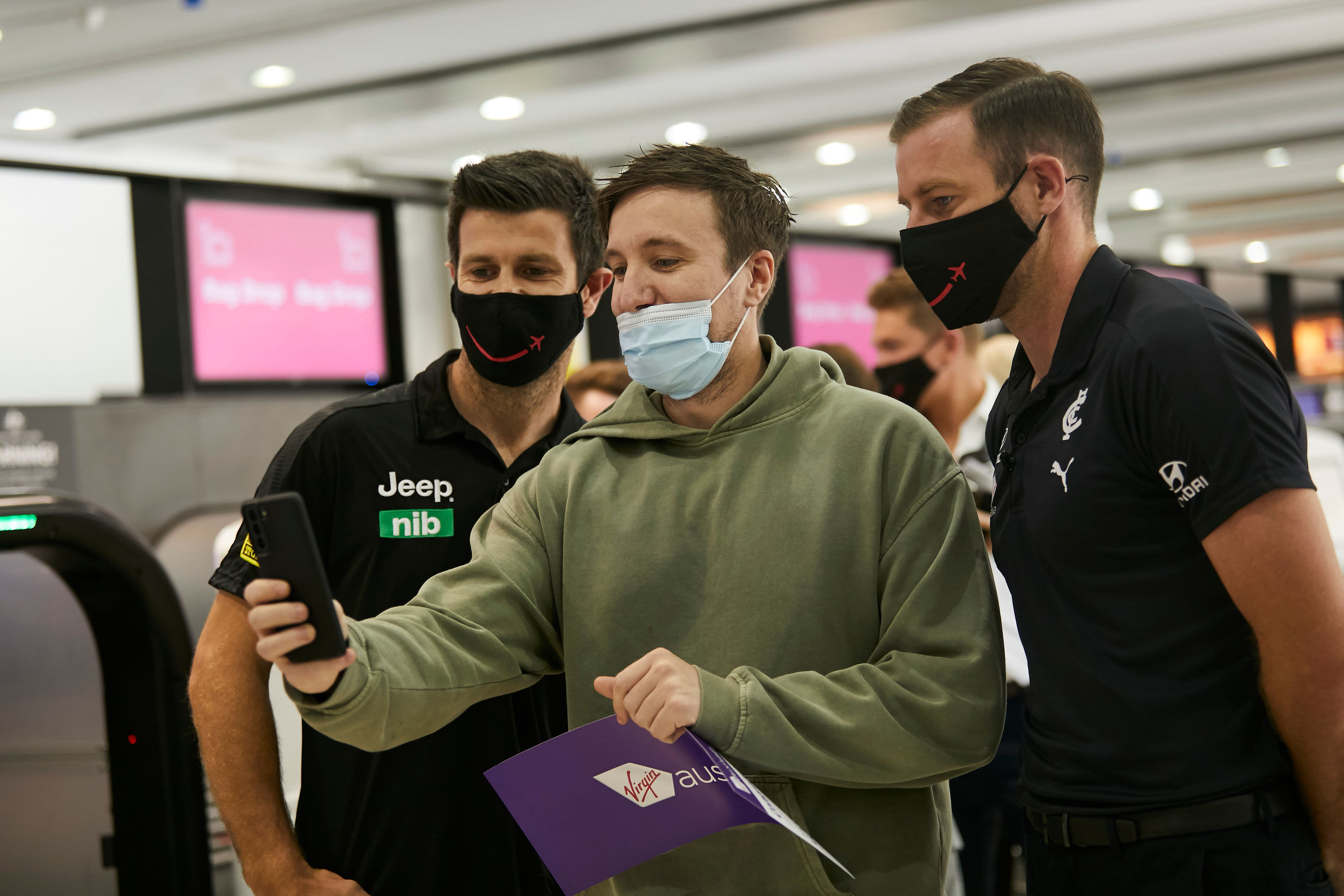 Trent Cotchin and Sam Docherty take selfies with fans at Melbourne Airport