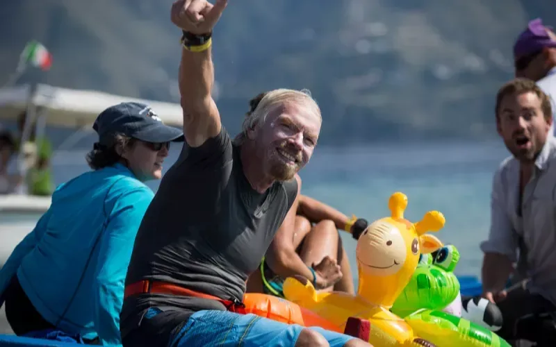 Richard Branson soaked from swimming giving a thumbs up to the camera