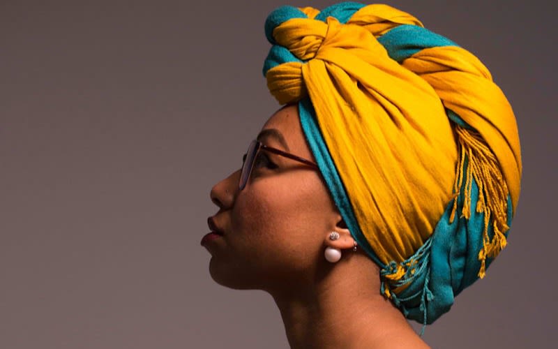 Yassmin Abdel Magied wearing glasses and a bright yellow and blue headscarf