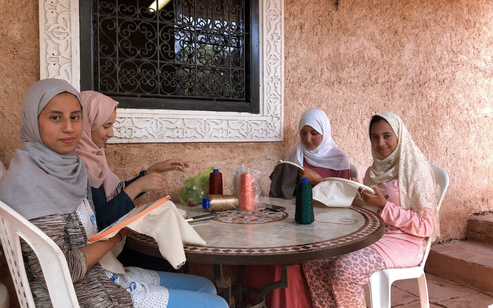 Women sitting at a table sewing at a project set up by the Eve Branson Foundation