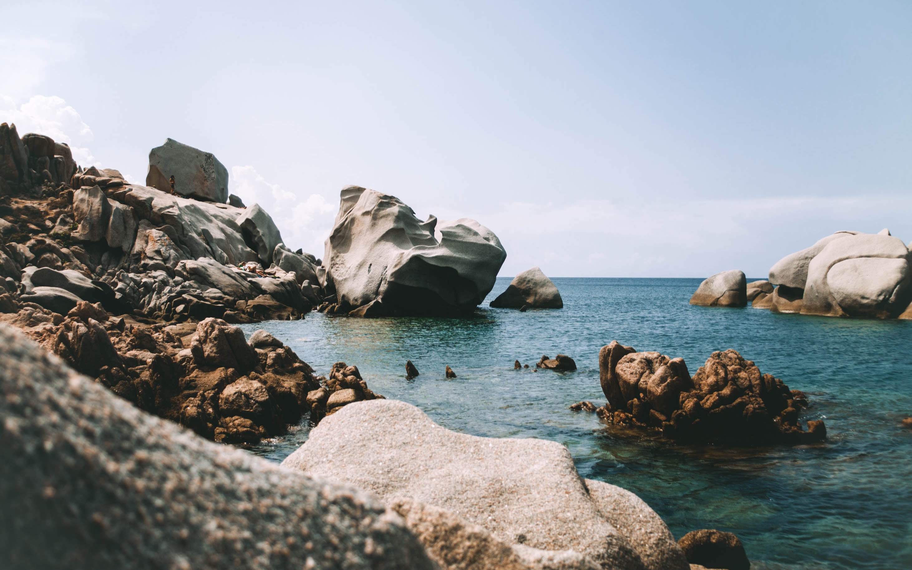 Image of blue water surrounded by some rocks.