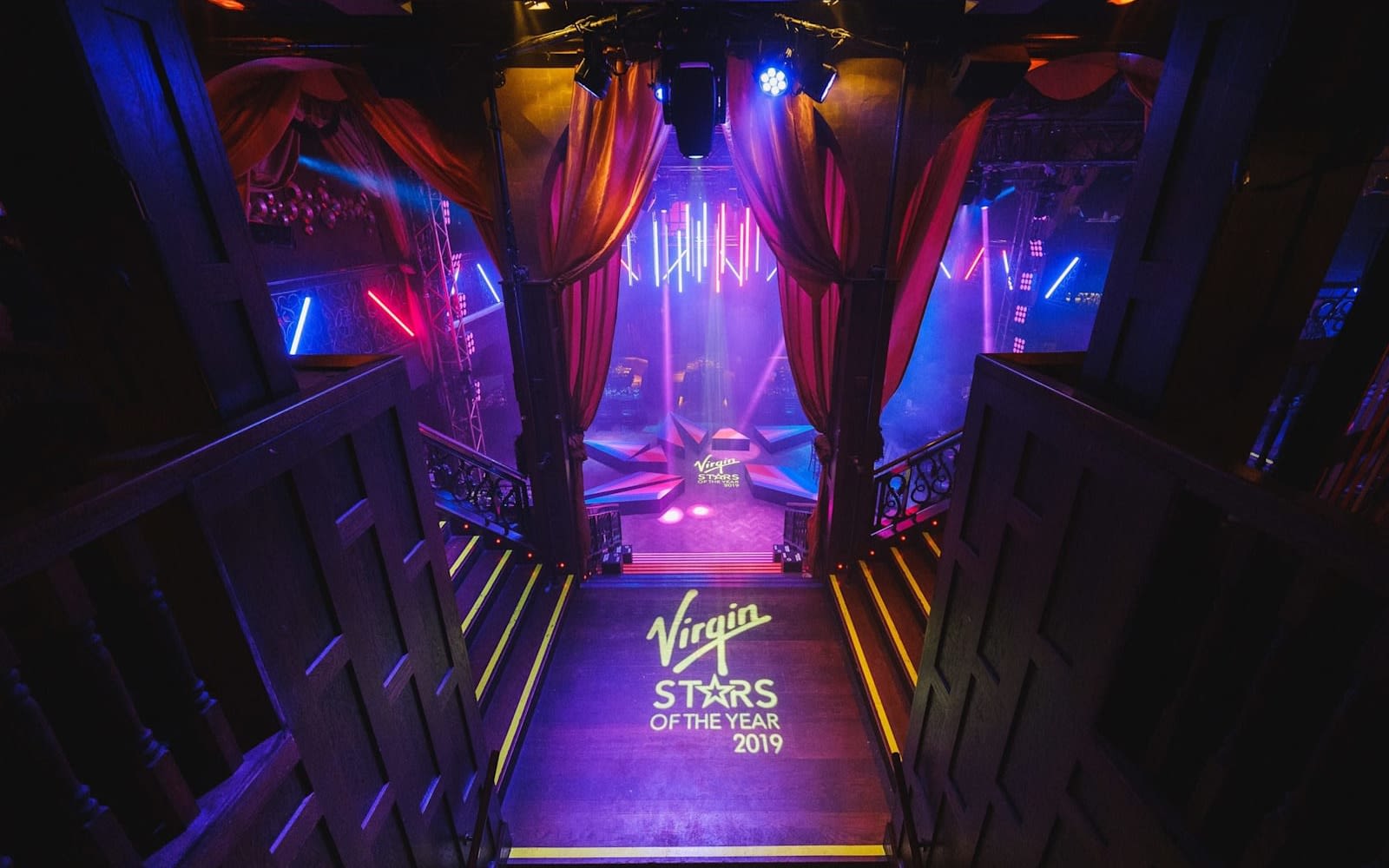 Bright lights shine on a dance floor, highlighting the words Virgin Stars of the Year 2019
