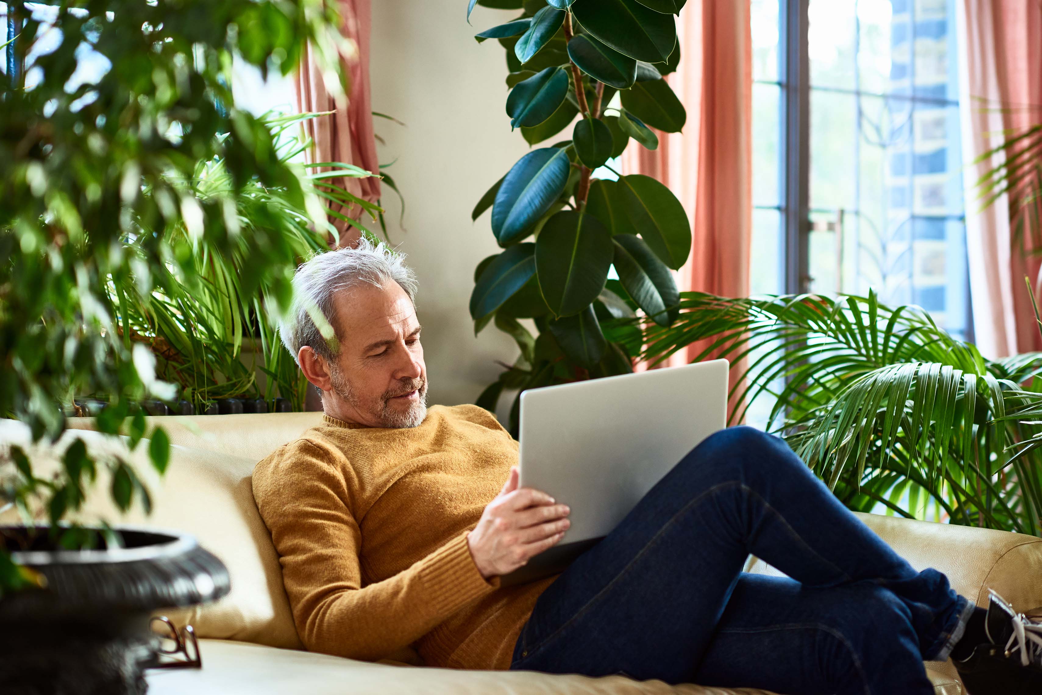 Man sitting down on a sofa with his laptop. 