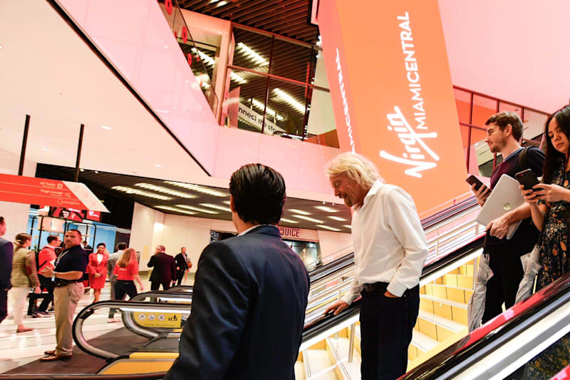 Richard Branson travelling down an escalator at Virgin Trains Miami Central station