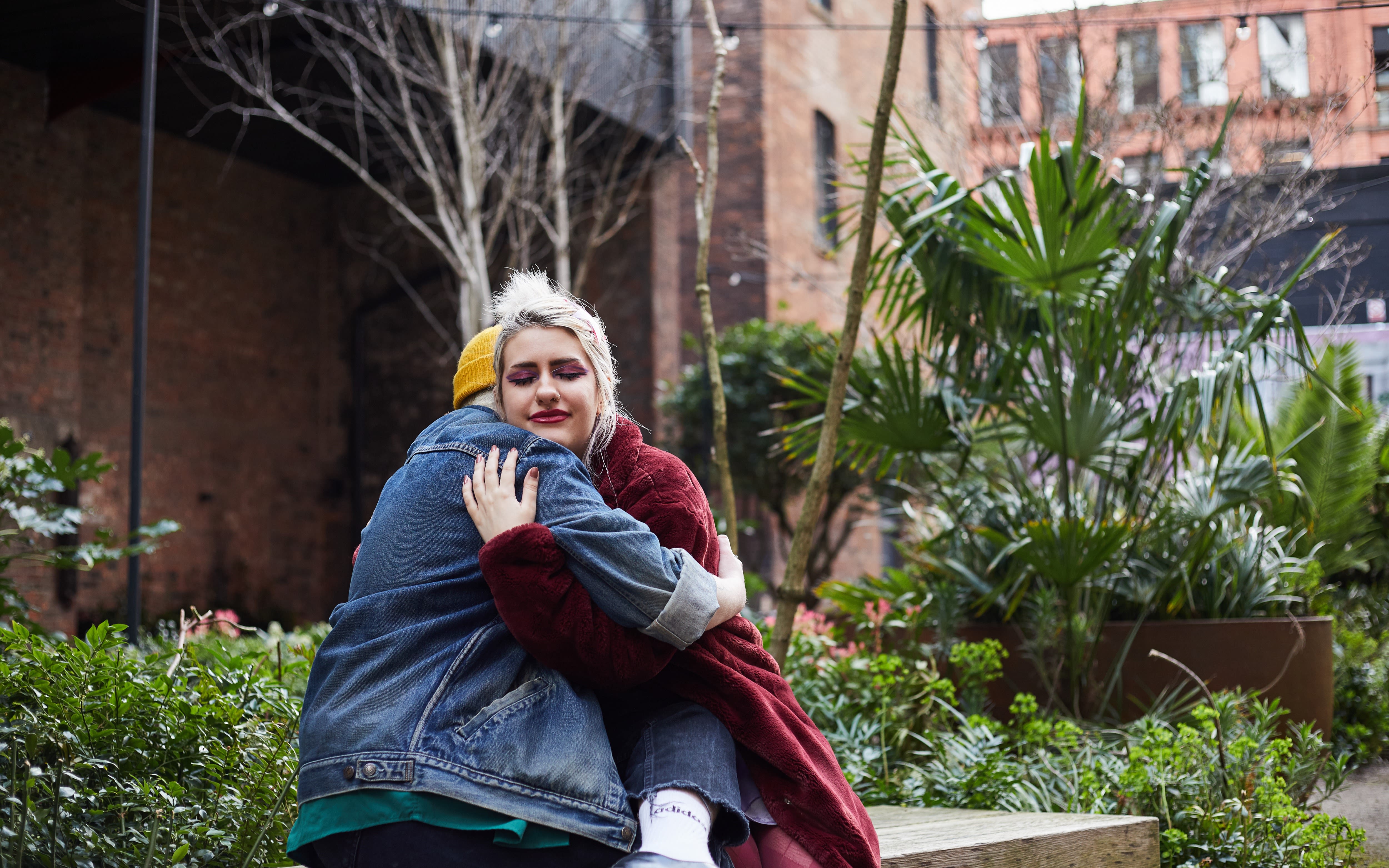 Image of two people hugging on a bench. 