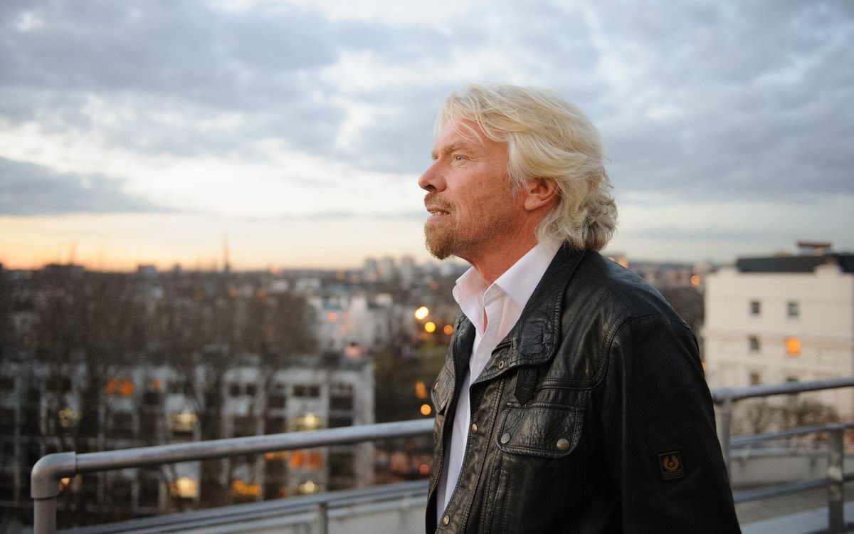 Richard Branson staring into the distant on top of a balcony overlooking a city