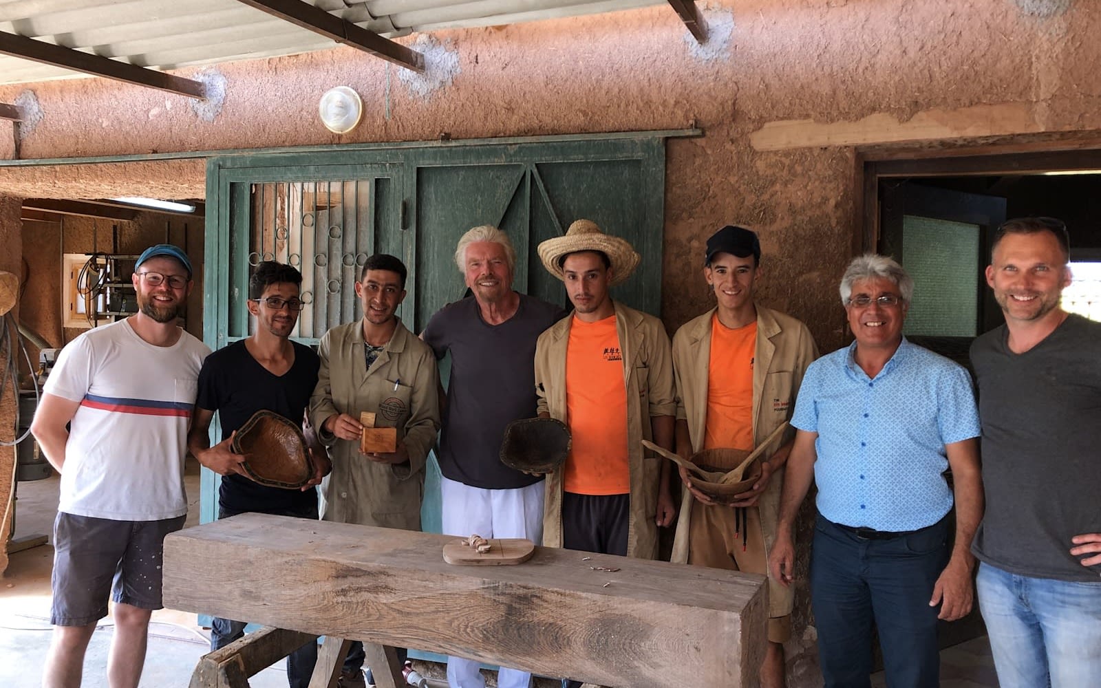 Richard Branson smiling and standing between a group of men from the Woodwork Centre
