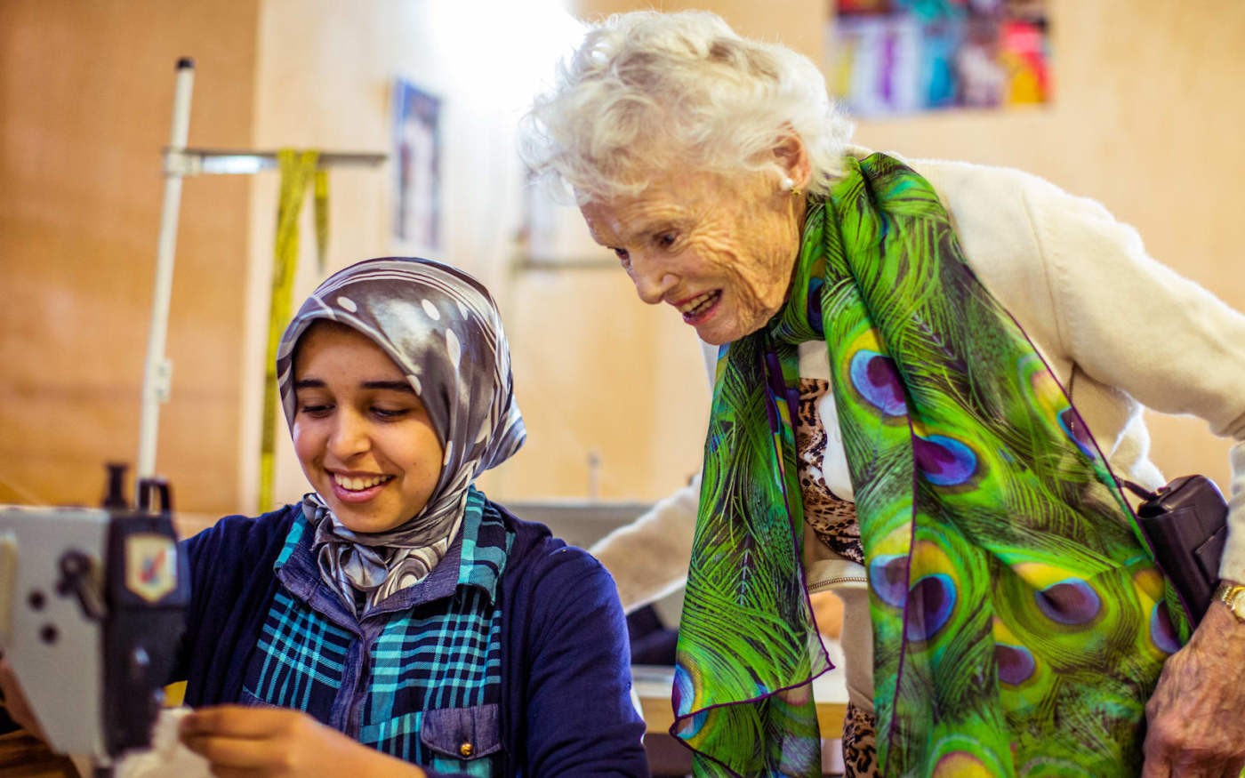Eve Branson interacting with a young girl sewing at the craft house 