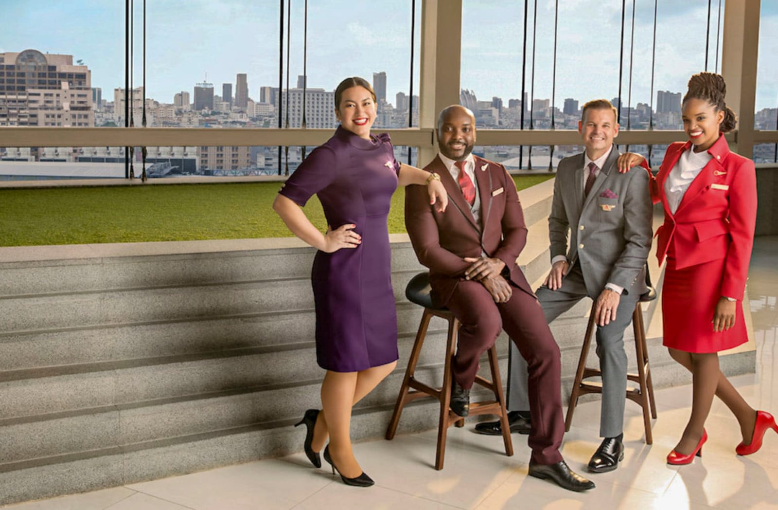 Four cabin crew members in the uniforms of Virgin Atlantic and Delta, looking at the camera, smiling