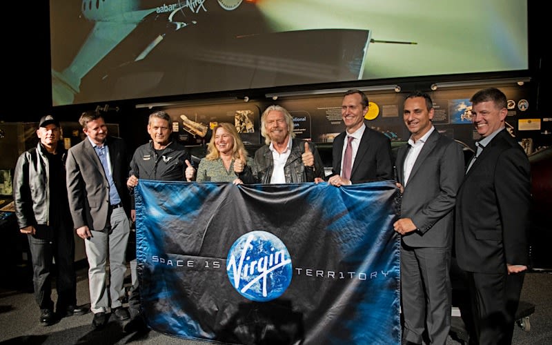 Richard Branson holds a flag saying Space is Virgin territory