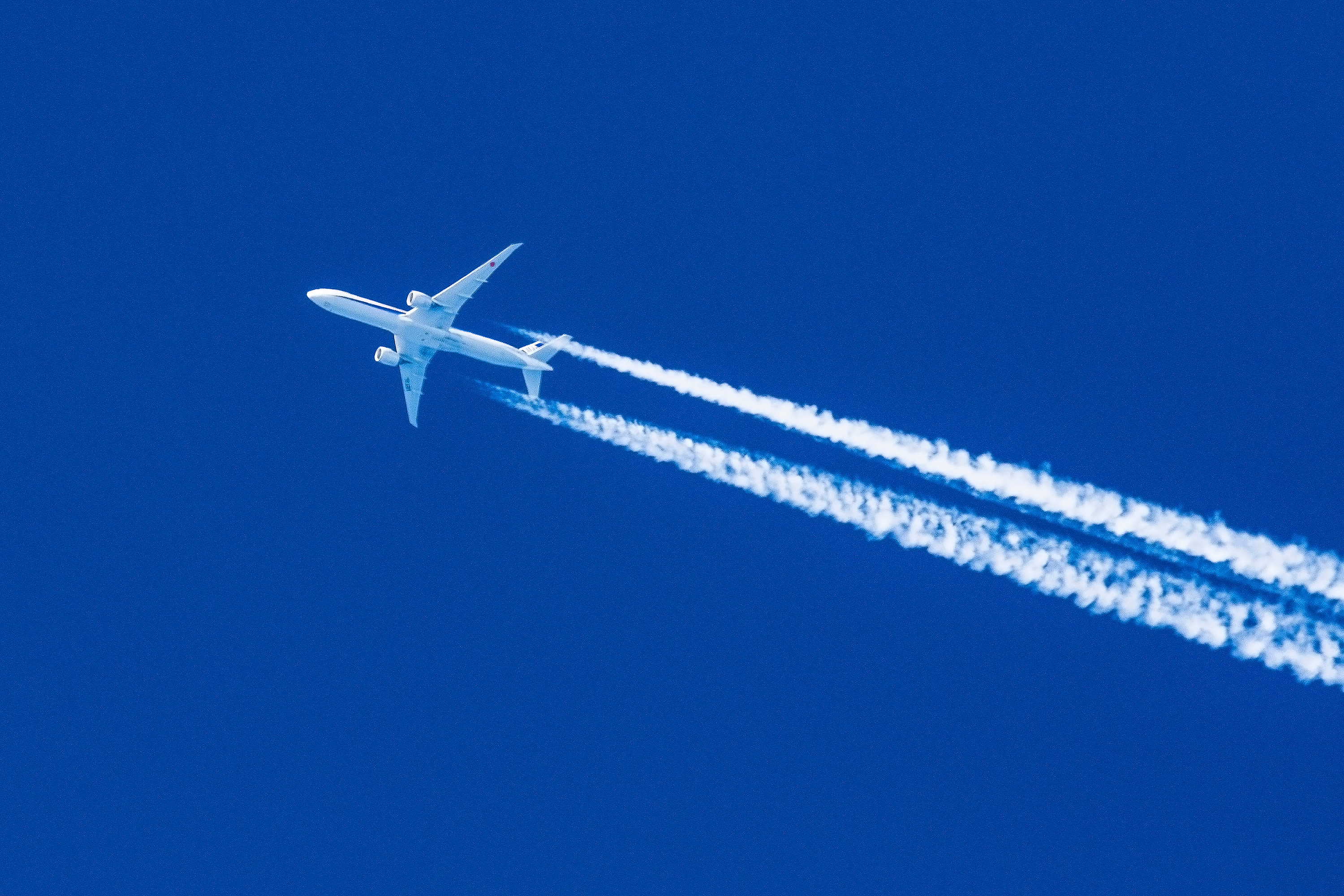 An aircraft flying in a blue sky with contrails coming out the back